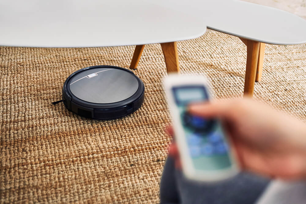 Will Your Roomba Fall Down The Stairs - Hand holding a remote controlling the robot cleaner