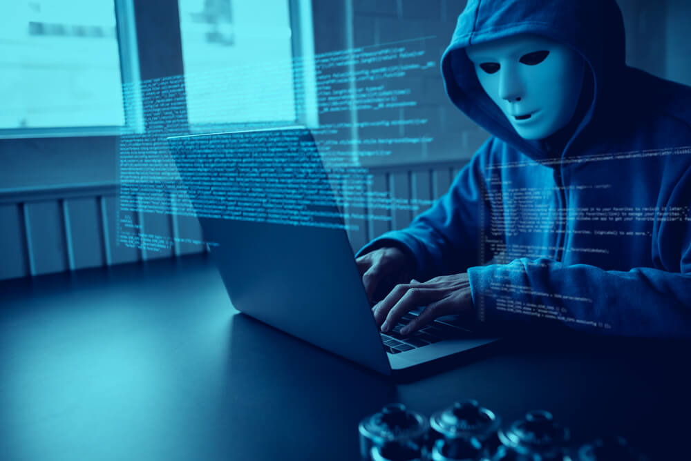 a hacker wearing a mask while doing a cyber attack