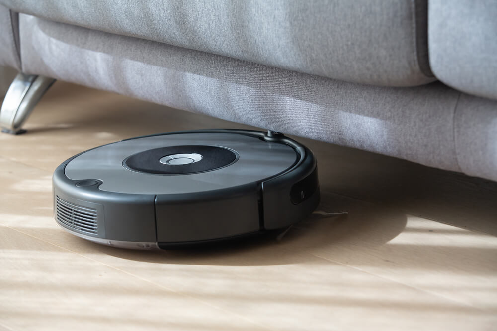 Robot vacuum gets stuck under a gray sofa