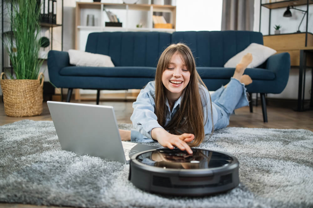 Will a Robot Vacuum Cleaner Roll Over a Threshold- a woman cheerfully operating the robot vacuum cleaner