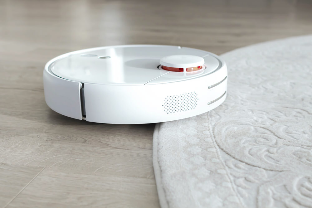 a white robotic vacuum cleaner trying to roll over the carpet
